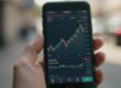 Main d'un trader avec un smartphone affichant des ETF.